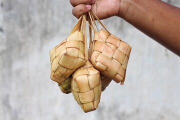Ketupat still wrapped in coconut leaves isolated on blurred background