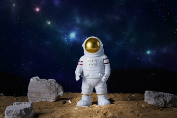 Figurine of astronaut over blue star sky background, copy space. Toy of spaceman. Space and space...