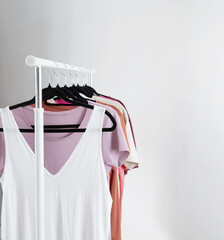 row of t-shirts on a hanger against a background of a white wall hanger - 790808154