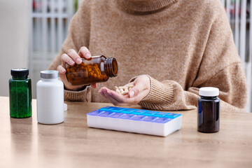 Female putting prescription pills and vitamins in a daily pill box organizer. Sorting nutritional supplements and antibiotics into weekly pills container. - 790808197