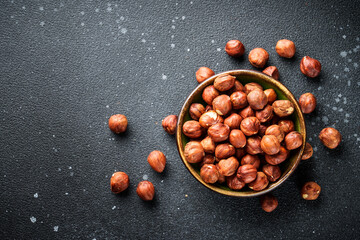 Hazelnuts in bowl at black background. Top view with copy space.