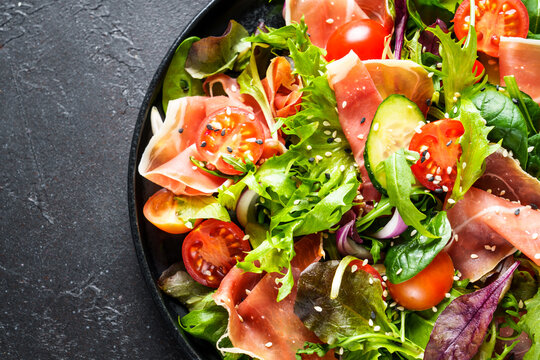 Green vegetable salad with snoked ham and sesame. Top view with space for text. Macro.