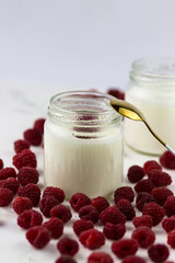 Homemade yogurt in glass jars. Delicious juicy raspberries on a white background