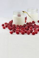 Homemade yogurt with raspberries. Jars of yogurt surrounded by raspberries. Space for text