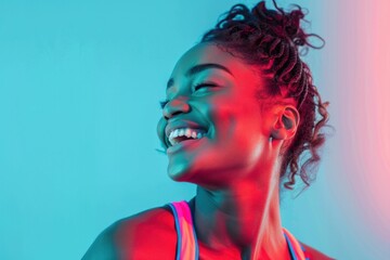 Portrait of a joyful African American woman smiling in front of vibrant blue and pink background