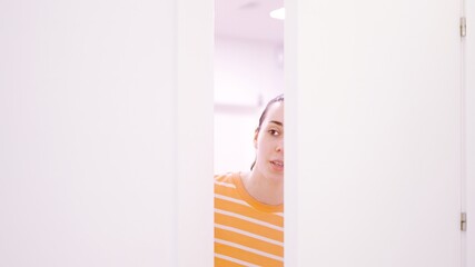 Woman peeping surreptitiously looking through a half-open door