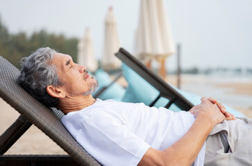 tranquil senior man with grey hair and beard sleeping on beach chair at seaside on summer time,older adult male relaxing in nature,concept of elderly pensioner lifestyle,holiday,travel,wellbeing