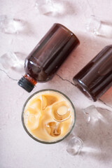 Cold brew coffee with milk and cold brew coffee in bottles with ice cubes top view