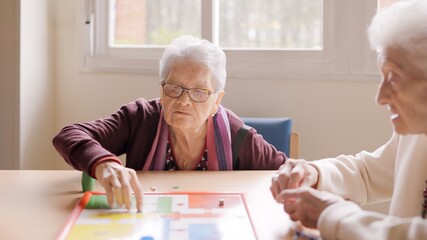 Two old friends playing board game in a nursing home