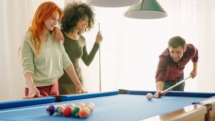 Group of young friends smiling playing billiards