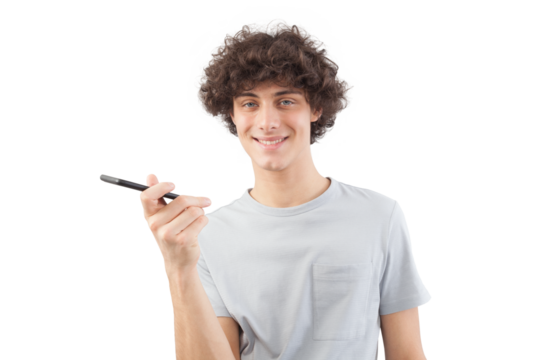 A young, handsome man smiles as he uses his smartphone, talking and listening with cellphone while looking into the camera with his blue eyes. He is isolated against a white background
