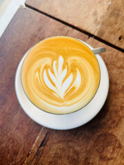 Top view of Hot latte coffee with latte art in a ceramic white cup on wood table