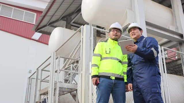 Two men in safety gear are looking at a tablet