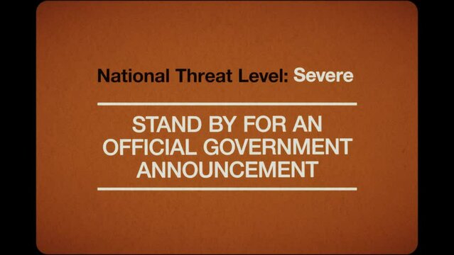 A TV caption card in a retro 1970s 16mm film style with the wording ‘National Threat Level: Stand by for an official government announcement’. The graphics are created in an analogue cardboard style.