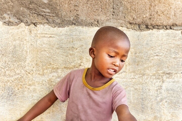 portrait of a village african child, in front of the wall of the house