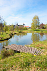 small lake with boardwalk, view to moated castle Schwindegg, upper bavaria