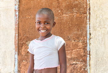 portrait of a village african child, in front of the wall of the house