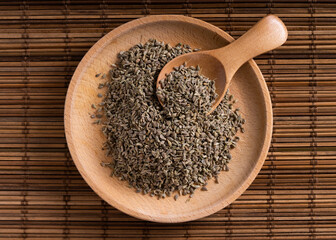 Fragrant anise seeds in the kitchen. Anise seeds in a wooden plate, top view. Pile of anise spice on wooden spoon.