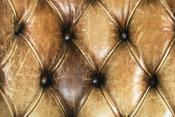 Warm genuine leather texture. Vintage light brown sofa with buttons for background. Decoration design. Luxury fashion and lifestyle concept. Upholstery artificial or genuine leather with rivets.