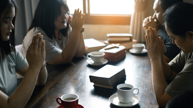 Christian woman held her Bible close as she joined hands with the group in prayer, their faith uniting them together in a religious bond during their prayer session. Group christian pray concept.