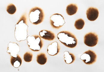 Collection of burnt holes in piece of paper isolated on white background