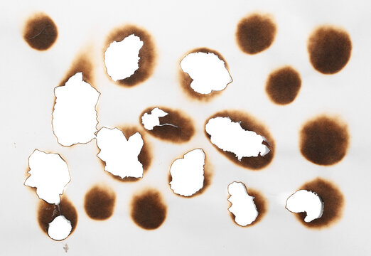 Collection of burnt holes in piece of paper isolated on white background