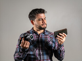 Hombre sosteniendo un celular y una cámara digital en expresión de duda y comparación. Fotografia de estudio con fondo blanco