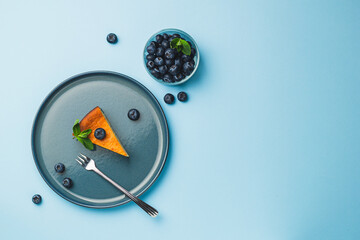 Cottage cheese cheesecake slice with fresh blueberry and mint on blue background, top view