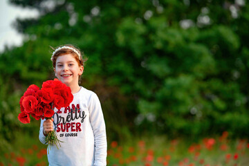Bambina sorridente con mazzo di fiori di papaveri, per la festa della mamma