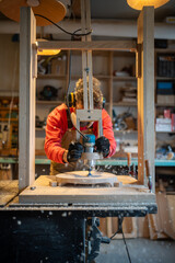 Male carpenter wearing protective noise-cancelling ear muffs, respirator working on drilling cnc...