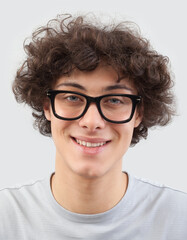 Smiling and handsome, the young man wears glasses. He looks into the camera with his blue eyes, man portrait with eyeglasses isolated against a gray background