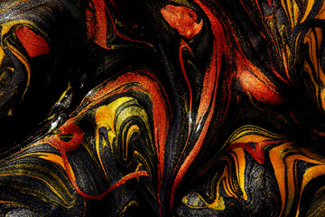 Closeup of gold, red and black fluid metallic paint textured background