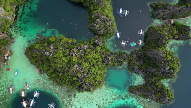 Aerial top view of tropical island. Boats in blue lagoons, rocks cliffs mountains and coral reef, Philippines, 4k
