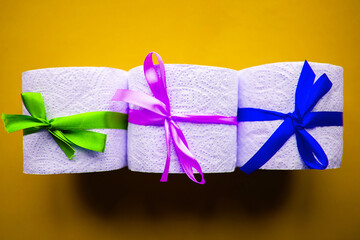 Toilet paper rolls with gift bows on bright yellow background. Quarantine concept