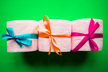 Toilet paper rolls with gift bows on bright green background. Quarantine concept