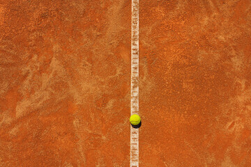  A yellow tennis ball lies on the clay court. Big panorama.