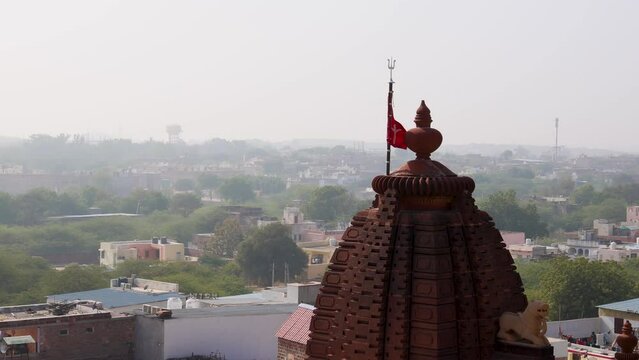 ancient hindu temple with waving holy flag and misty city background from at morning