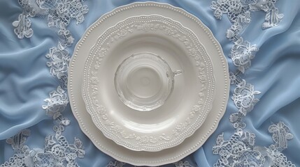   A white plate atop a blue-covered table, featuring a white doily underneath Nearby stands a cup and saucer - obrazy, fototapety, plakaty