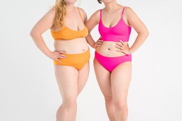 Two overweight women with cellulitis, fat flabby bellies, legs, hands, hips and buttocks on gray background, obese female body, liposuction and plastic surgery concept
