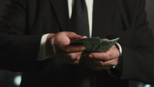 Close-up of hands of a businessman in formal business suit counting a stack of banknotes. Concept of reasonable and careful financial management