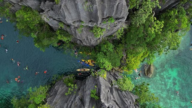 Aerial top view of tropical island with people. Tourists leisure in blue lagoons, rocks cliffs mountains and coral reef, Philippines, 4k