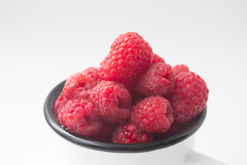 Fresh red ripe organic raspberry in a mug