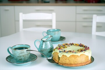 Ciasto, sernik, tort, pistacje z kawą na stole w kuchni