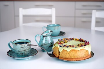 Ciasto, sernik, tort, pistacje z kawą na stole w kuchni