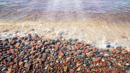 A beautiful seashore with wet polished pebbles and clear glowing calm water