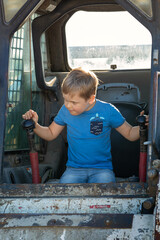 Vertical portrait of a small boy with a focused and serious face expression driving a small bulldozer