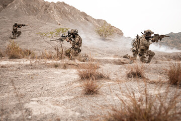 Soldiers in camouflage uniforms aiming with their rifles.ready to fire during military operation in...