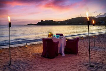 A beautiful, romantic candelight dinner setup at a tropical beach during sunset time