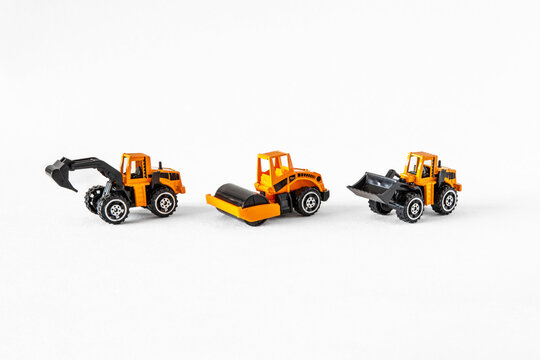 Yellow and black toys of public works vehicles on a white background