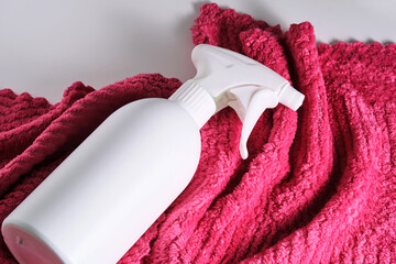 Cleaning product with a sprayer on a background of a red microfiber cloth.